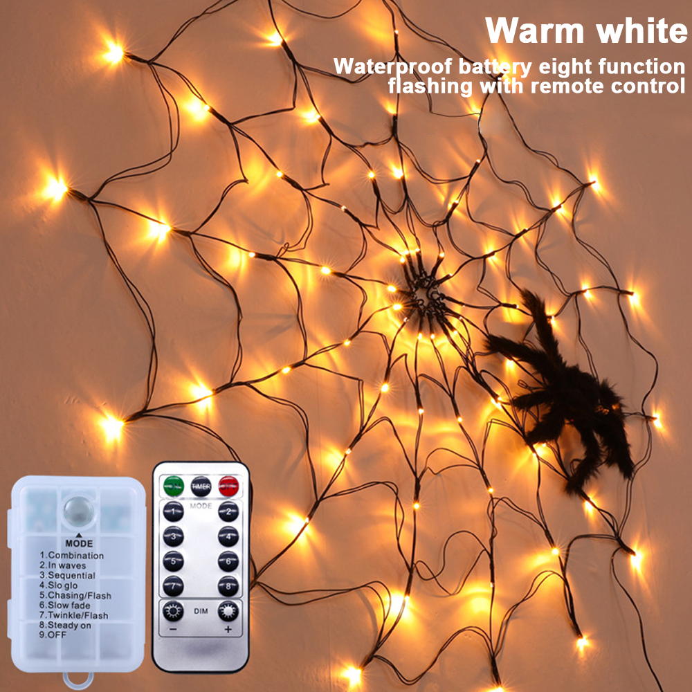 Eine Spinnennetzdekoration mit warmweißen Lichtern, einer schwarzen Spinne, einer Fernbedienung und einem Batteriekasten.