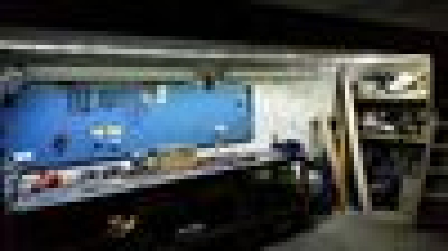 Garageninnenraum mit einem Auto. Blaue Wand im Hintergrund. Holzrahmen und eine Metallstange sind sichtbar.