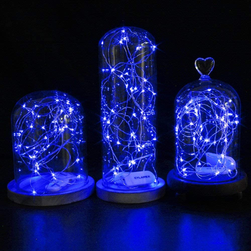 Drei Glaskuppeln mit blauen LED-Lichtern. Jede Kuppel steht auf einem Holzsockel. Der Hintergrund ist schwarz.