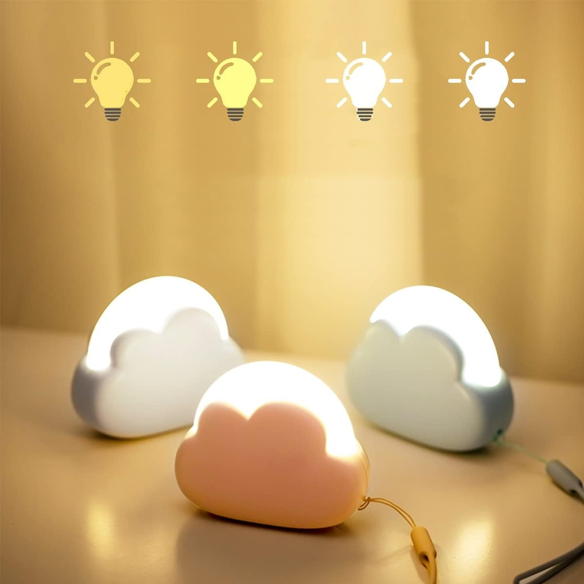 Drei wolkenförmige Nachtlichter stehen auf einem Tisch. Oben befinden sich Glühbirnen-Icons. Die Lichter sind weiß und pfirsichfarben.
