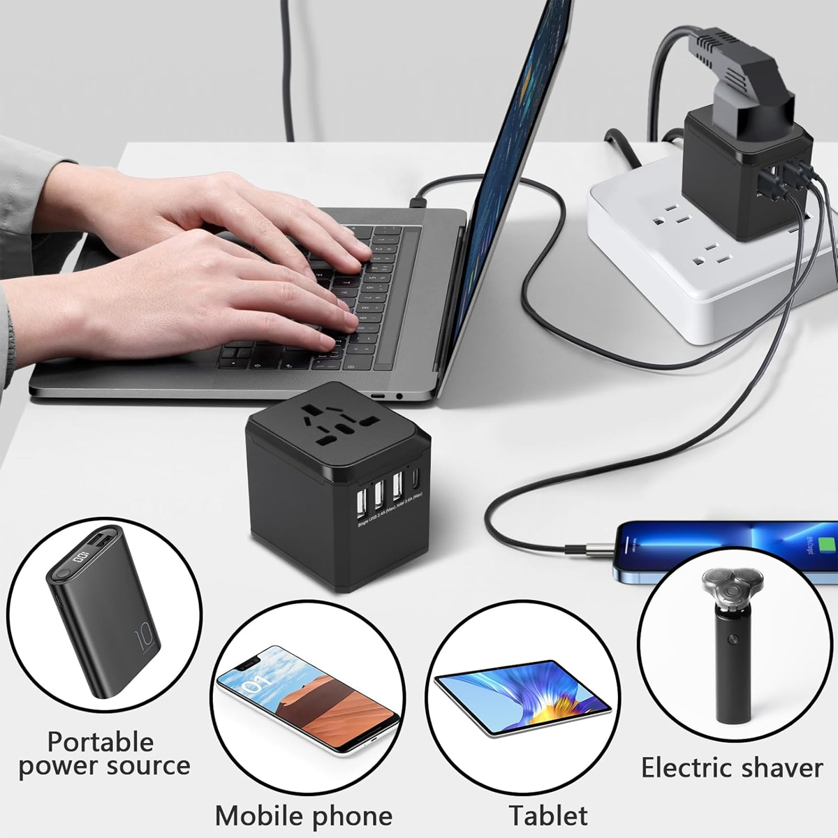 Laptop in Benutzung, mit Adapter und verschiedenen Geräten: Powerbank, Telefon, Tablet und Elektrorasierer, alle schwarz-weiß.