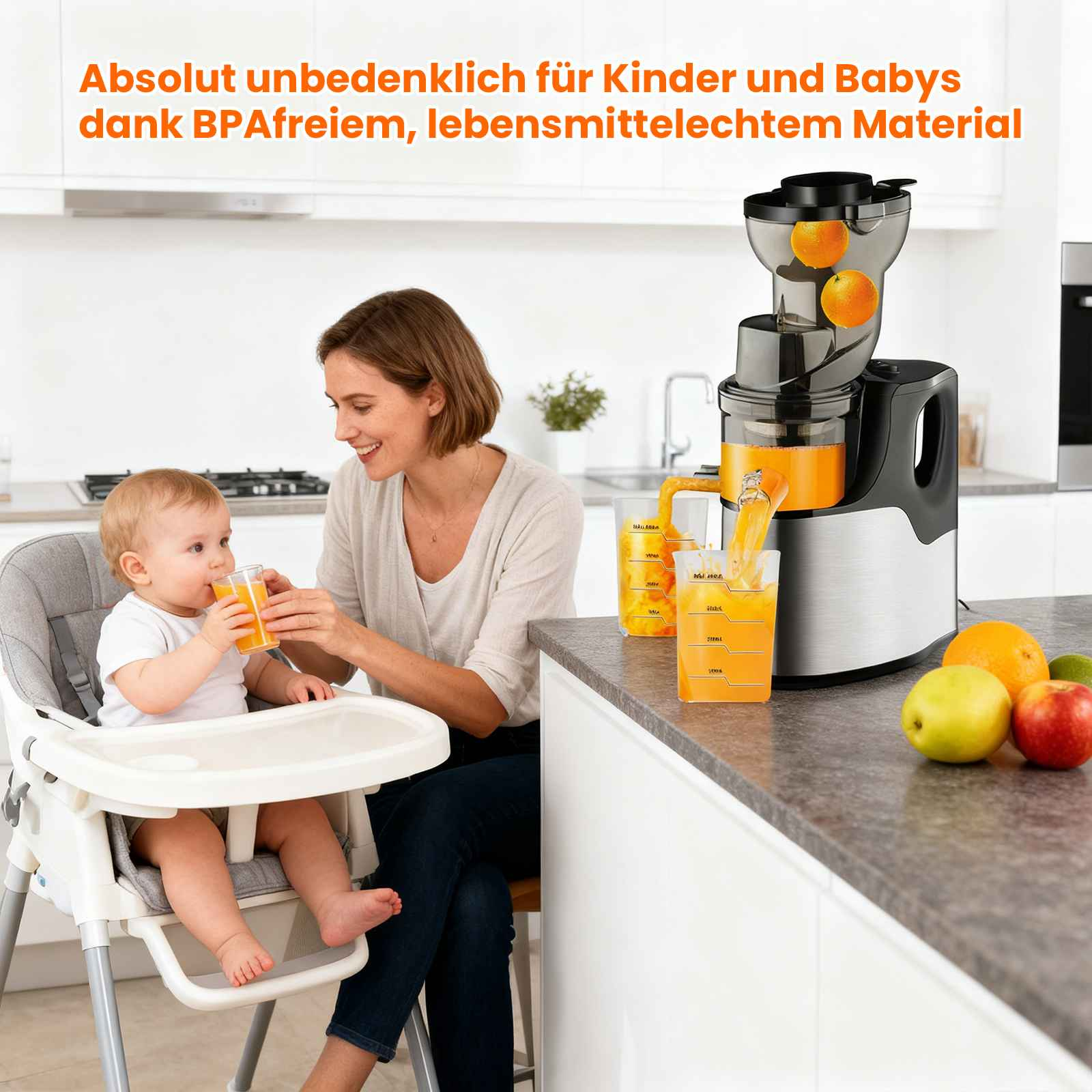 Eine Frau gibt einem Baby im Hochstuhl Saft. Auf der Theke stehen ein Entsafter und Früchte.