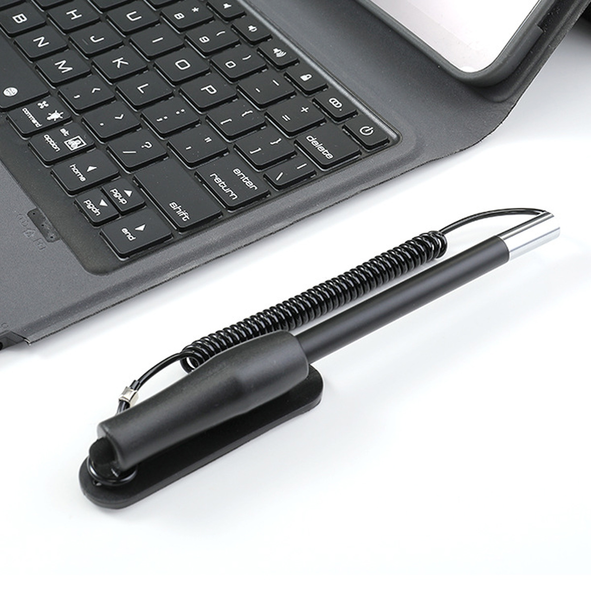 Eine schwarze Tastatur mit einem schwarzen Stift befindet sich auf einer weißen Oberfläche. Die Tastatur ist teilweise sichtbar. Der Stift steht im Fokus.