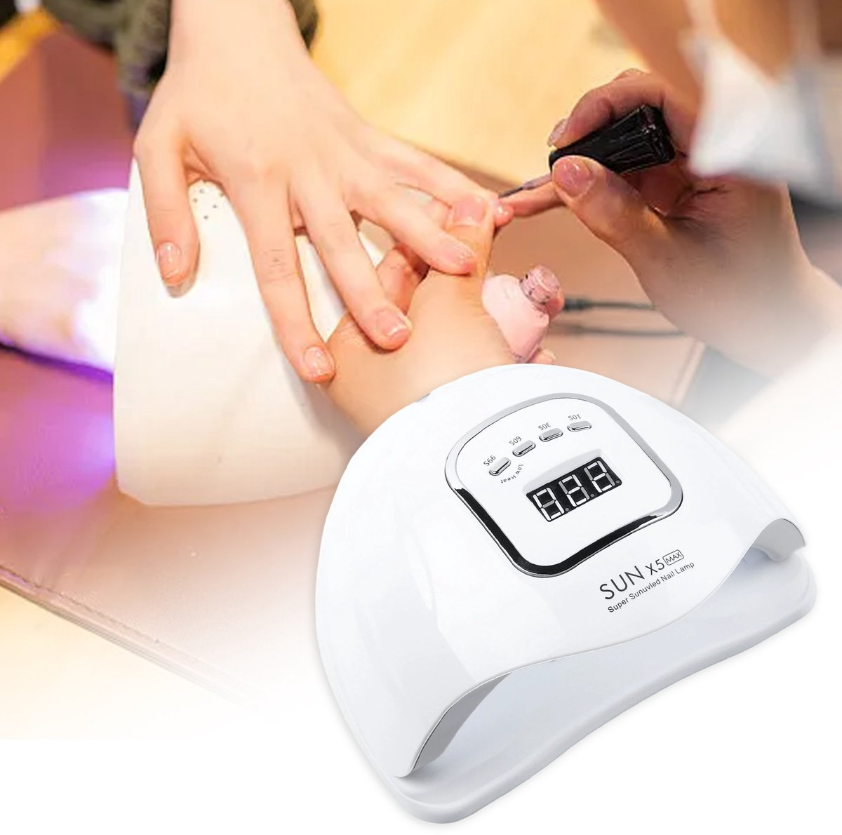 Jemand bekommt die Nägel gemacht. Eine weiße Nagellampe befindet sich im Vordergrund. Eine andere Person trägt Nagellack auf.