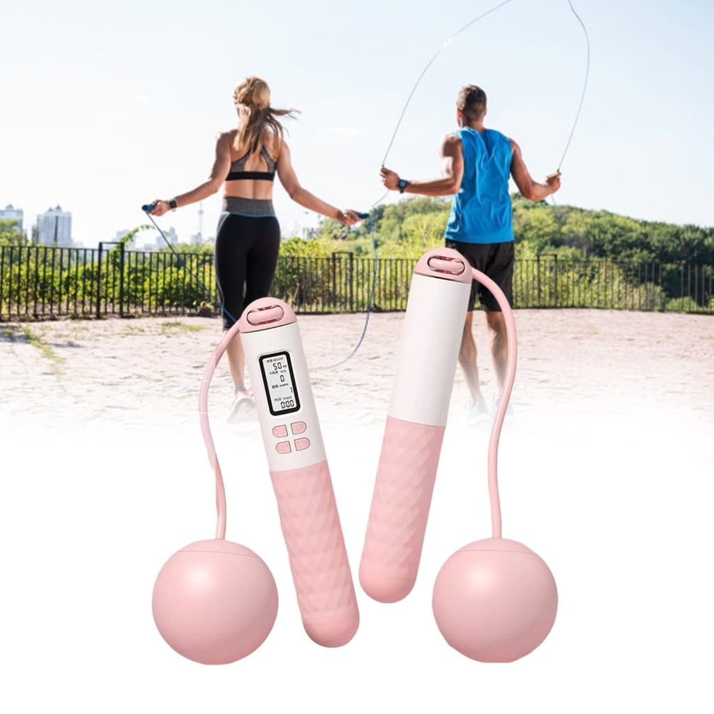 Zwei Personen springen draußen Seil. Rosa Springseile sind im Vordergrund. Personen tragen Sportkleidung. Sonniger Tag mit Bäumen im Hintergrund.