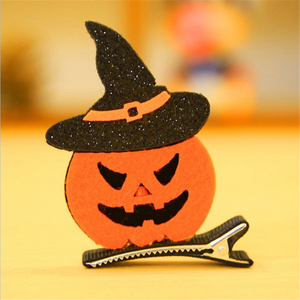 Ein Halloween-Haarclip. Er zeigt ein orangefarbenes Kürbisgesicht mit einem schwarzen Hexenhut und einem silbernen Clip.
