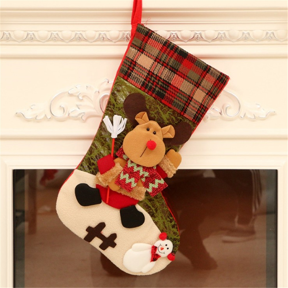 Weihnachtsstrumpf mit Rentier- und Schneemann-Dekorationen, rot, grün und beige, hängt an einem Kamin.