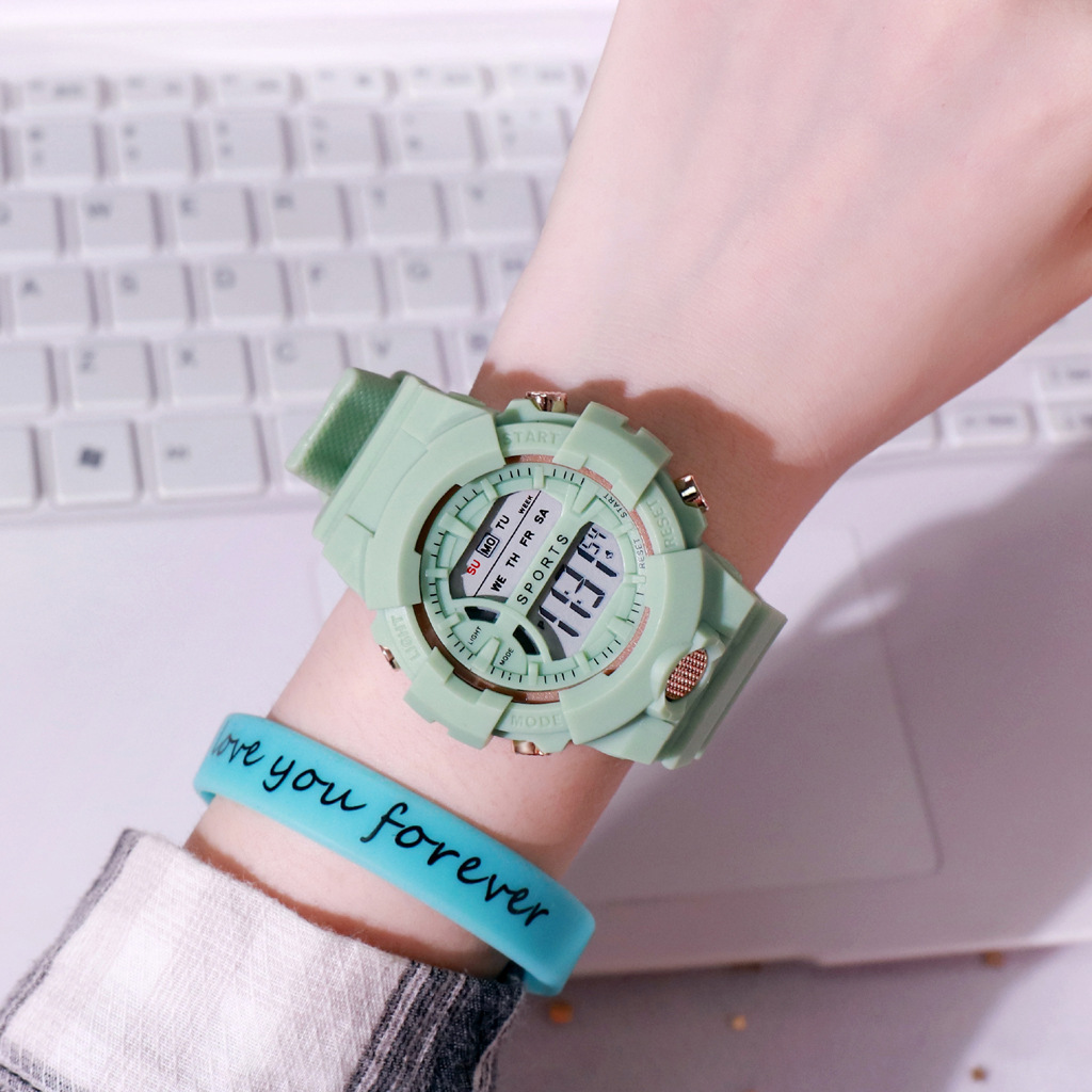 Hand mit grüner Digitaluhr und blauem Armband mit der Aufschrift 'love you forever' über einer Tastatur.
