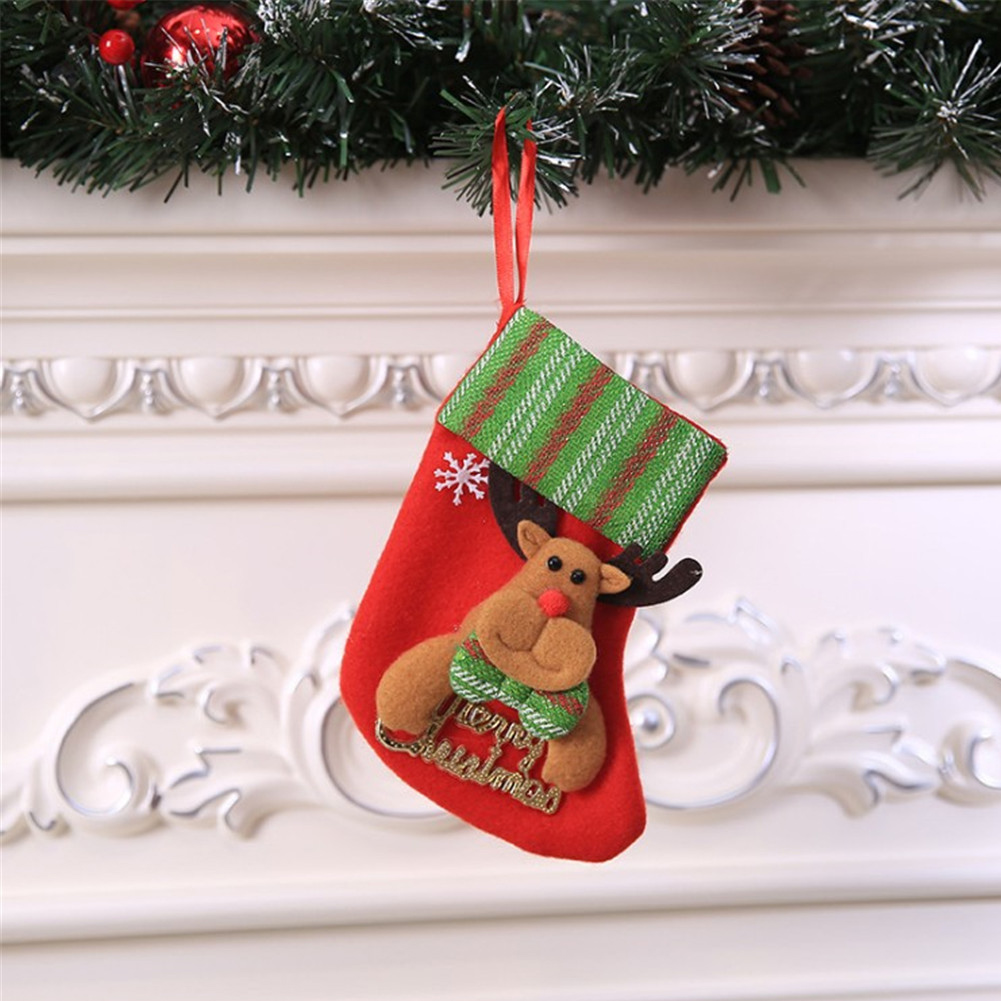 Ein roter Weihnachtsstrumpf mit Rentierverzierung hängt an einer grünen Girlande. Der Hintergrund ist eine weiße, verzierte Wand.