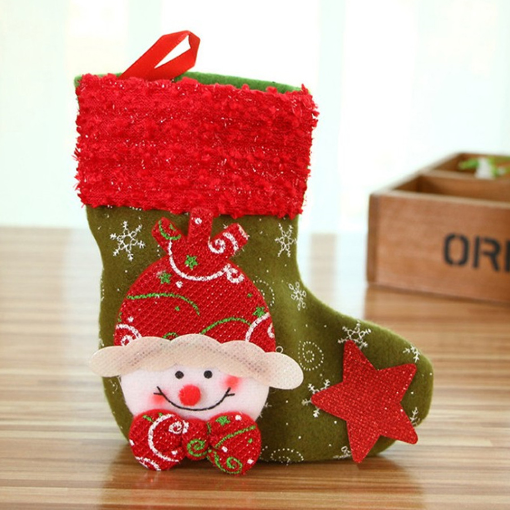 Ein Weihnachtsstrumpf mit einem Schneemann-Gesicht und einem roten Stern auf einem Holztisch. Der Strumpf hat grüne und rote Farben.