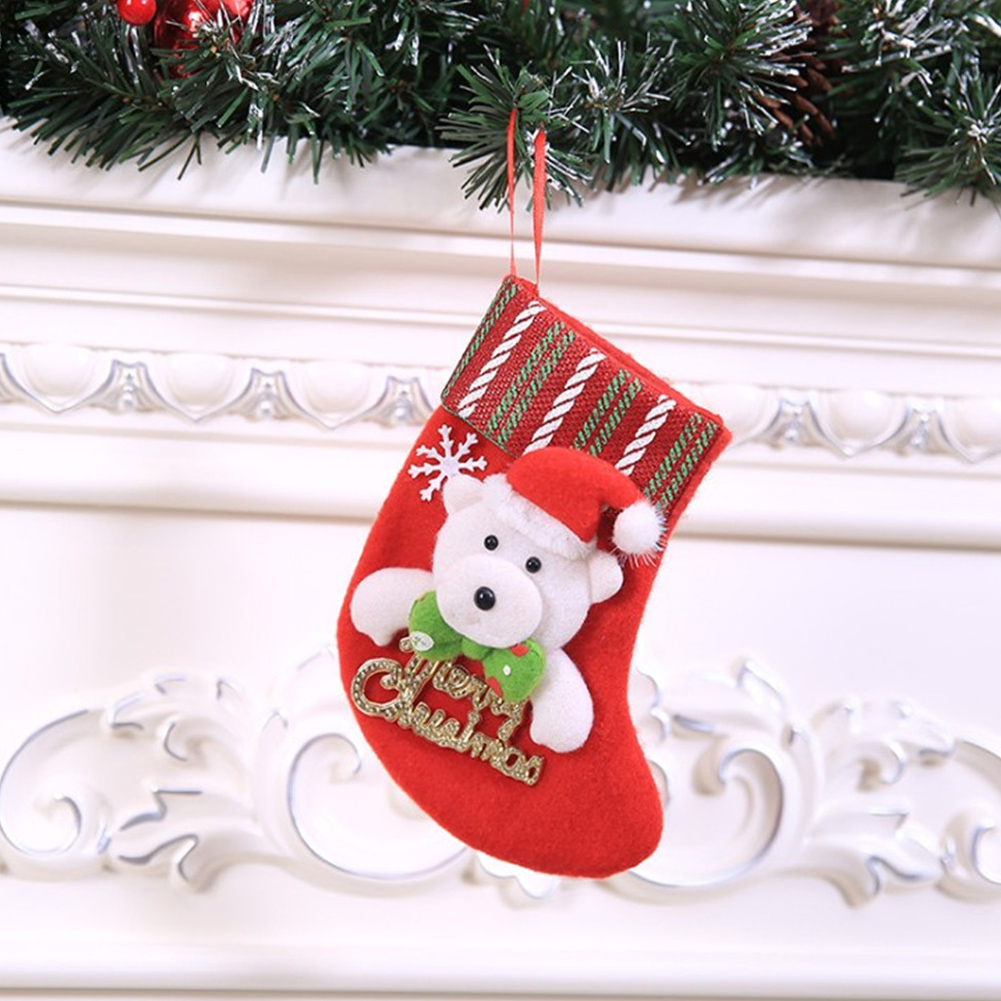 Ein roter Weihnachtsstrumpf mit einem Eisbären und einem Weihnachtsmannhut hängt. Er ist mit einer Schneeflocke und 'Merry Christmas' verziert.