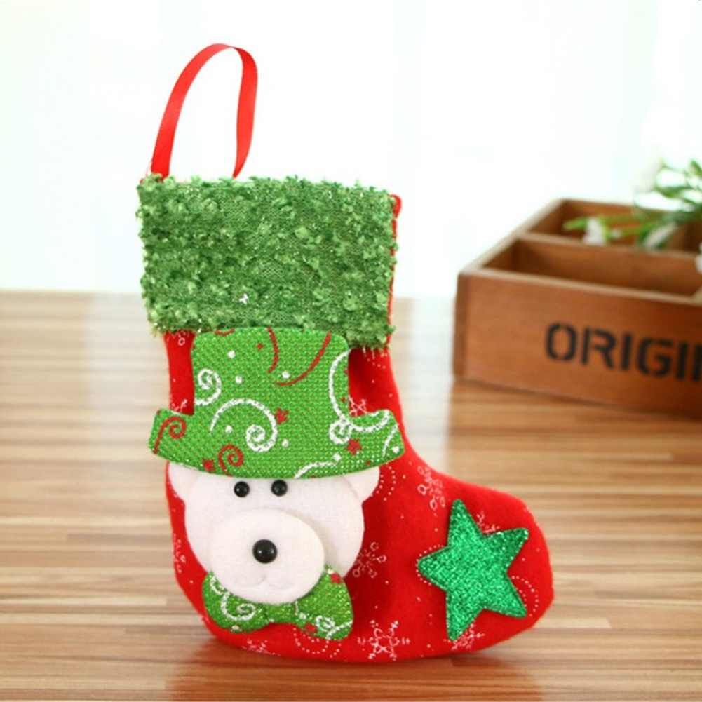 Ein roter Weihnachtsstrumpf mit Bärengesicht, grünem Hut und Stern. Er hat einen roten Griff und steht auf einer Holzoberfläche.