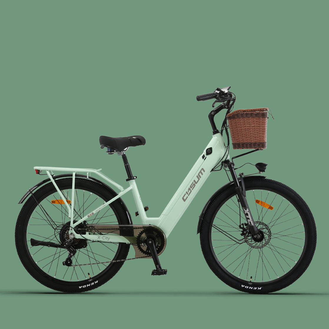 Miętowy zielony rower elektryczny z brązowym wiklinowym koszem z przodu i czarnymi oponami na zielonym tle.