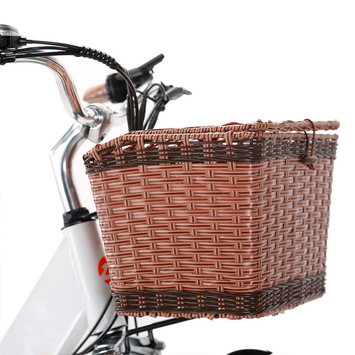Zbliżenie roweru z brązowym wiklinowym koszem z przodu. Rower jest biały i ma czarną kierownicę.