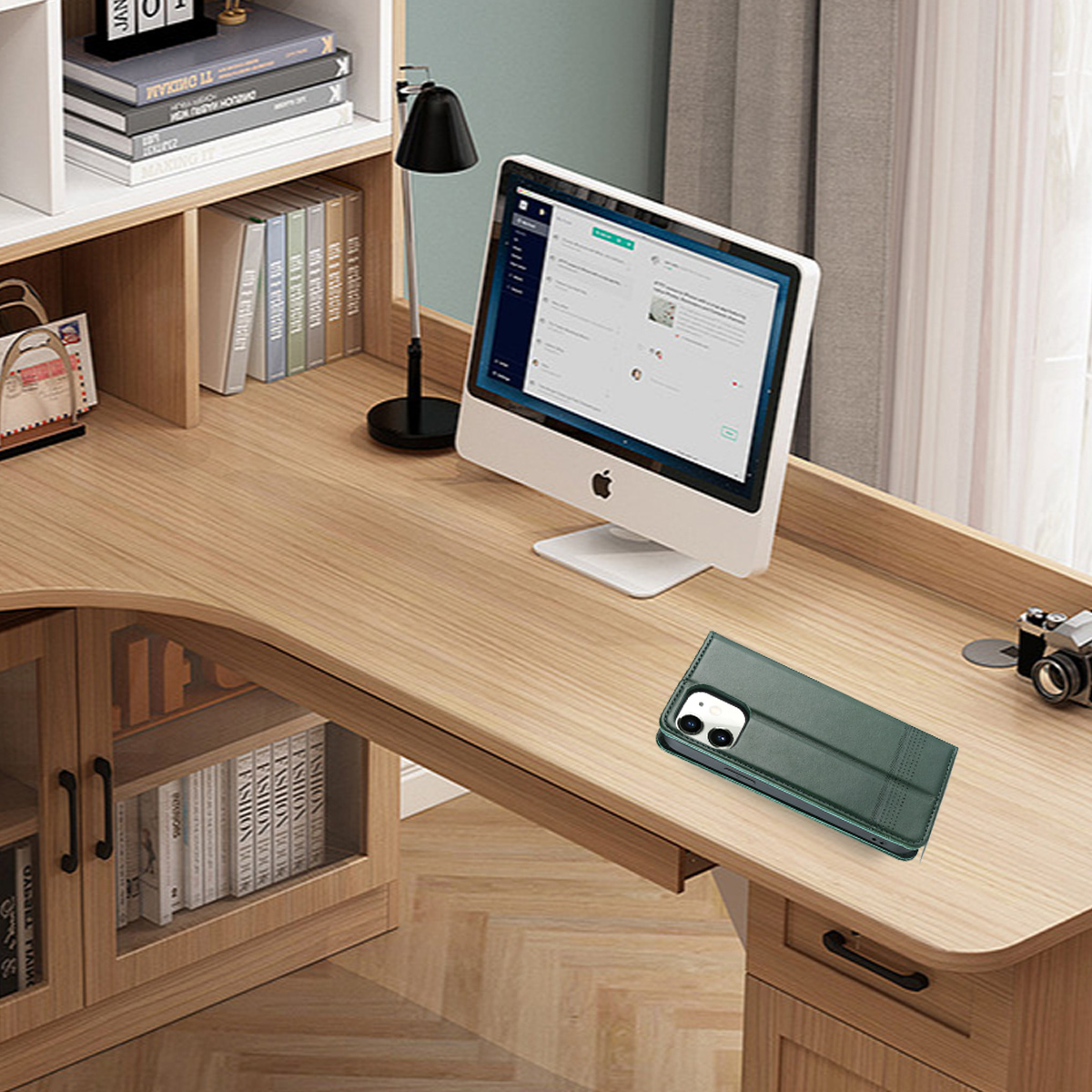 Ein Schreibtisch mit Computer, Büchern und Handyhülle. Der Schreibtisch ist aus Holz. Der Computerbildschirm zeigt eine Website.