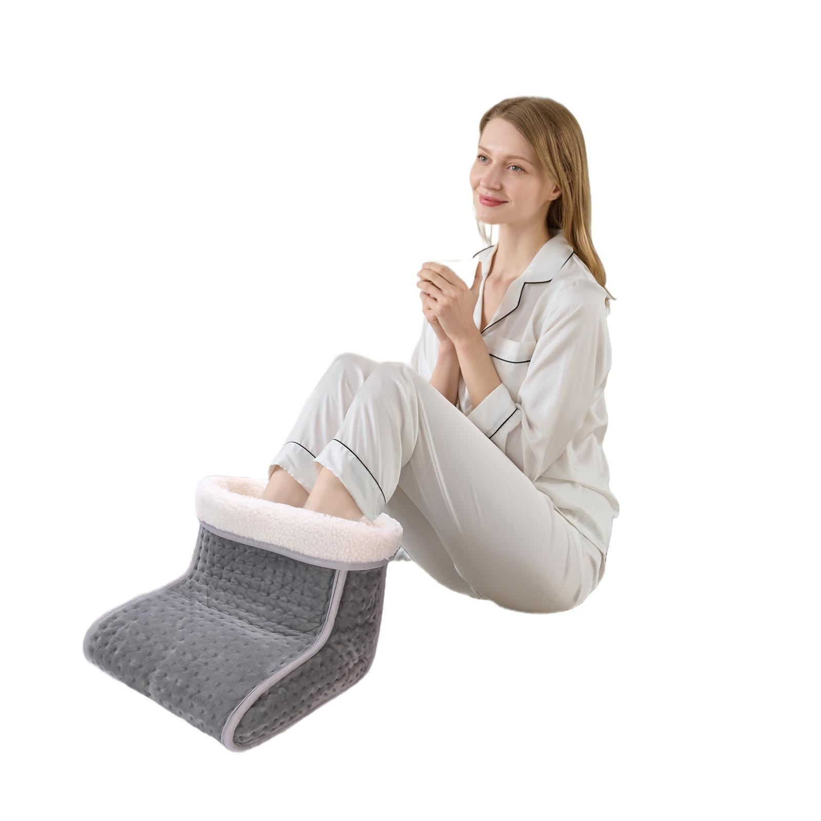 Frau im Pyjama mit Füßen in einem grauen Fußwärmer, hält eine Tasse. Der Hintergrund ist weiß.