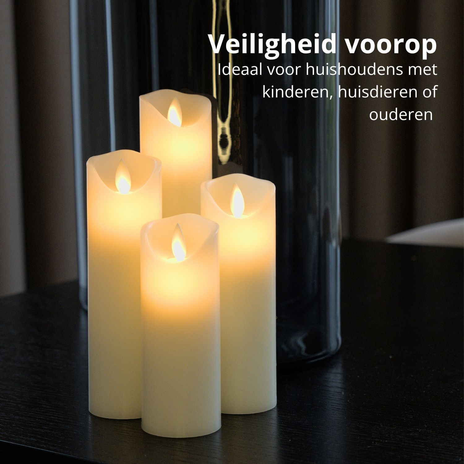 Vier brennende, elfenbeinfarbene Kerzen auf einem dunklen Tisch. Eine hohe, schwarze Vase im Hintergrund.