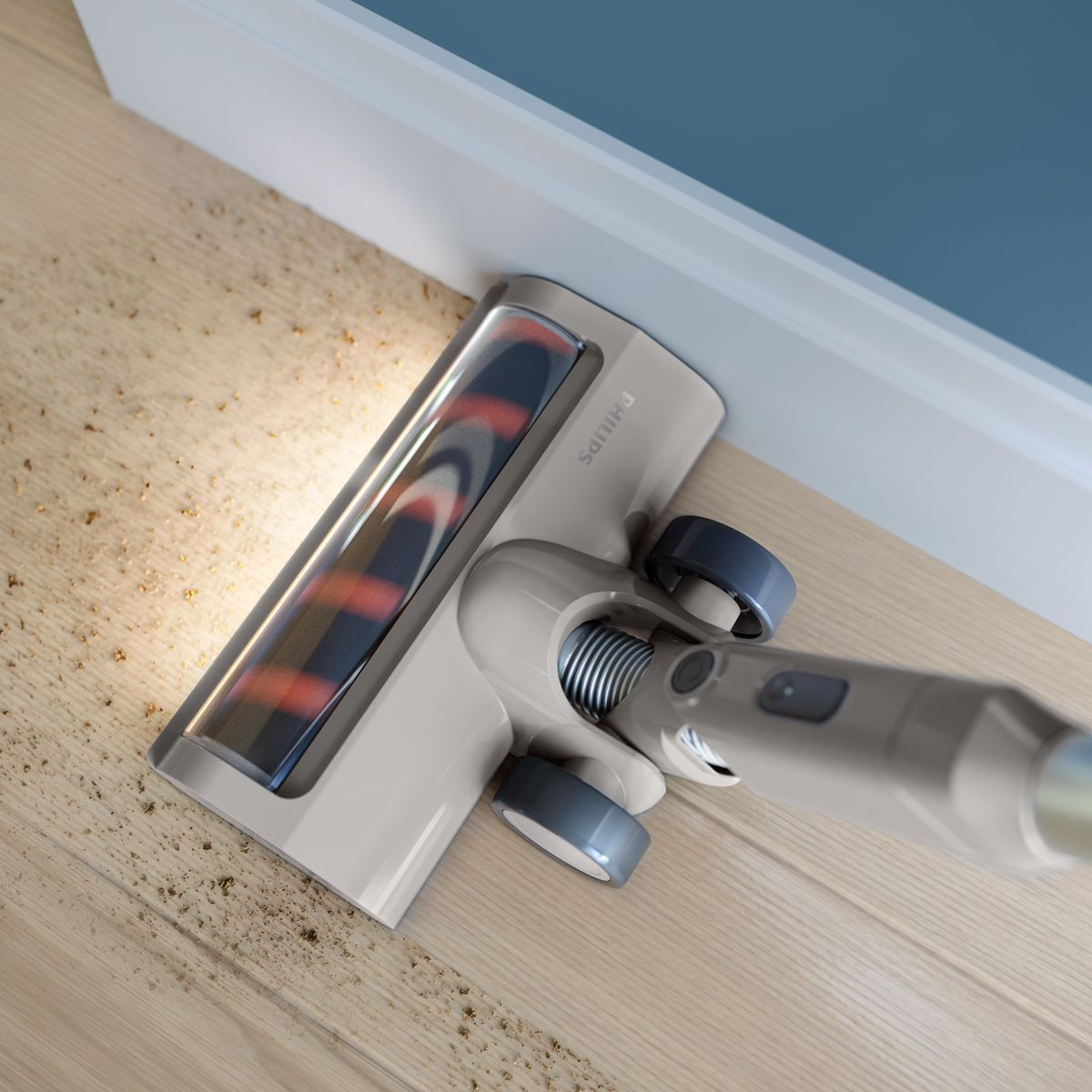 Głowica odkurzacza Philips czyści drewnianą podłogę. Widoczny jest kurz i zanieczyszczenia. Ściana i listwa przypodłogowa są w tle.