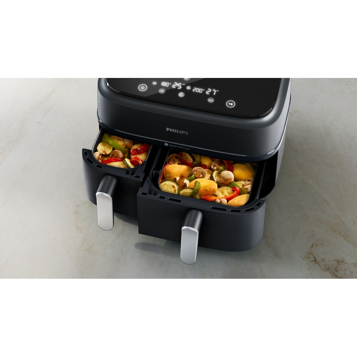 Czarna frytownica powietrzna Philips z dwiema komorami wypełnionymi gotowanymi warzywami. Na górze znajduje się wyświetlacz cyfrowy.