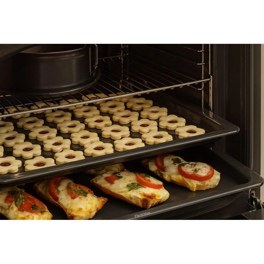 Forno con biscotti e pizze. Vassoio superiore con biscotti a fiore, medio con tortiera, inferiore con pizze al pomodoro.