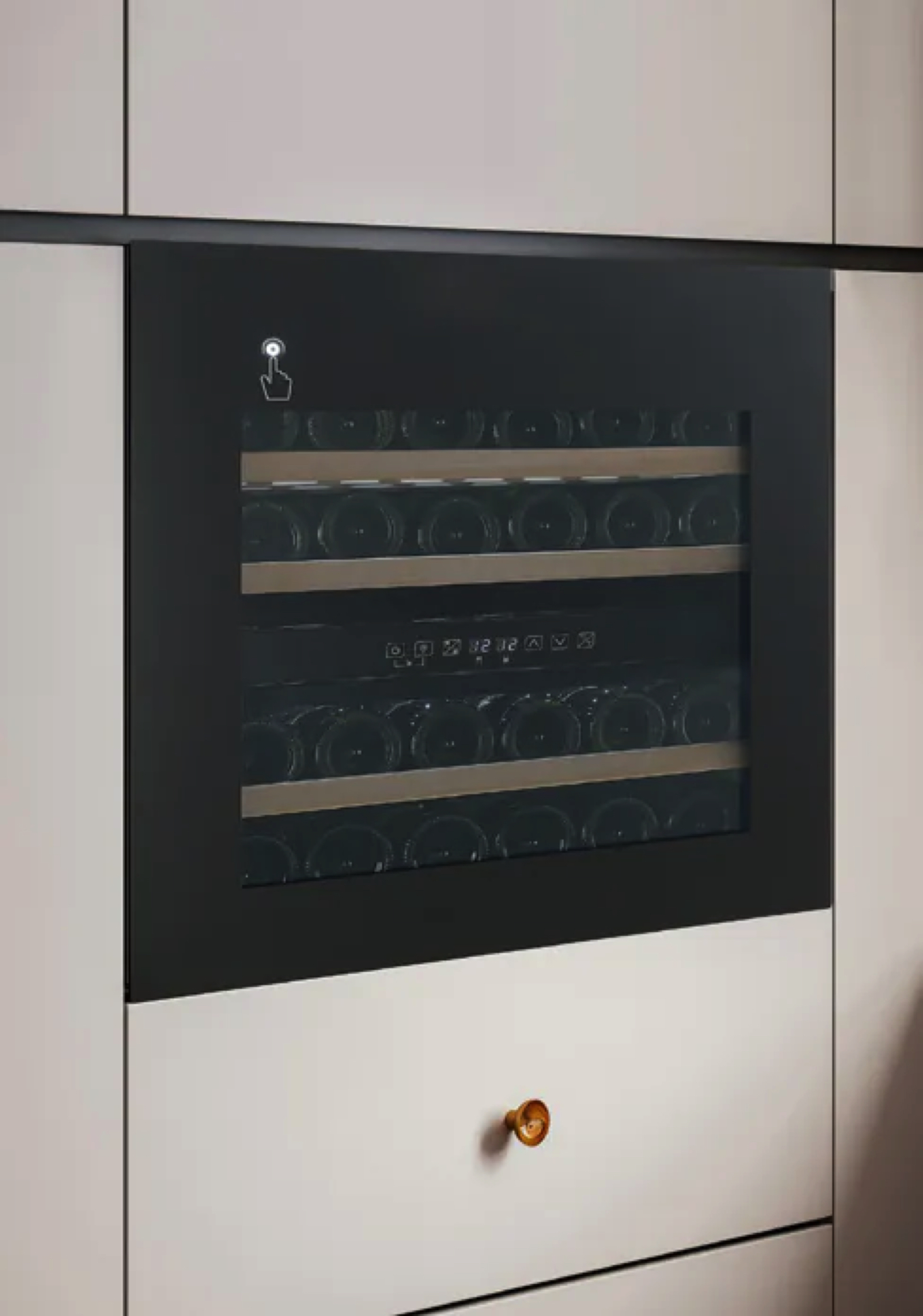 Un frigo per vino a incasso con molte bottiglie. Un cassetto con maniglia dorata sotto.