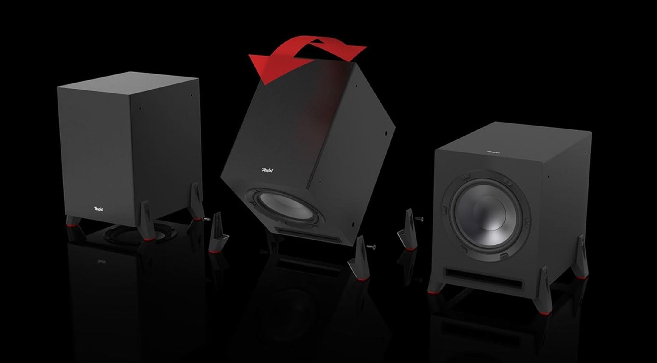 Drei schwarze Teufel-Subwoofer mit roten Akzenten. Einer ist mit einem roten Pfeil geneigt. Alle auf schwarzem Hintergrund.
