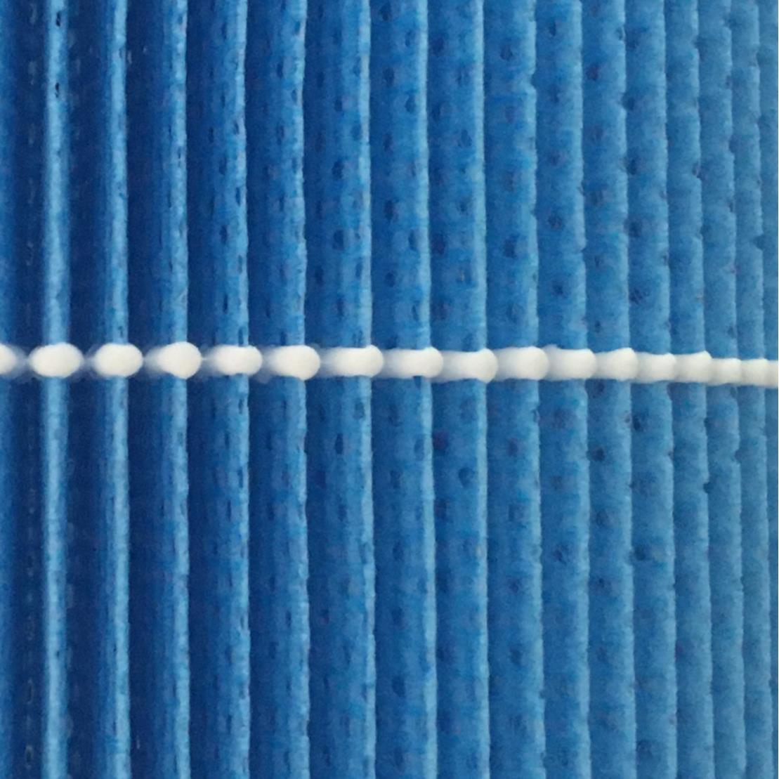 Nahaufnahme eines blauen Luftfilters mit vertikalen Rippen und einer horizontalen weißen Schnur aus verbundenen Zylindern.