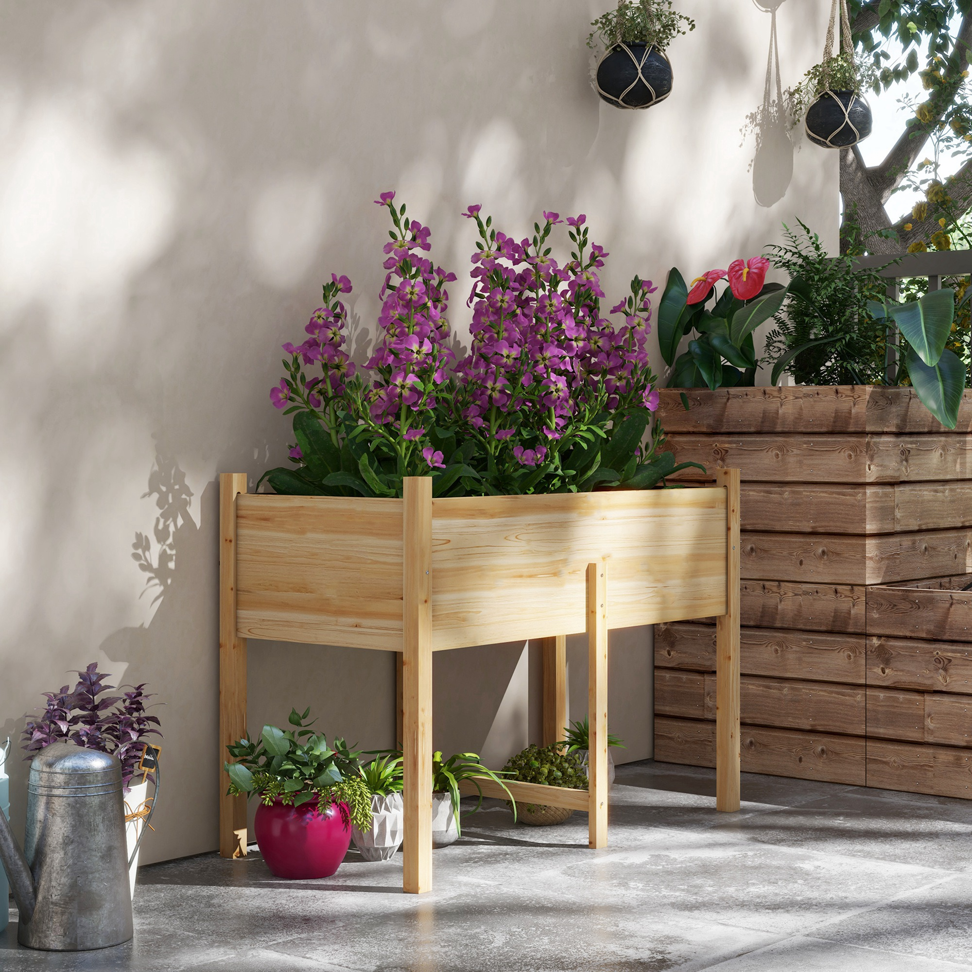 Fioriere in legno con fiori viola, piante verdi e cesti appesi su un patio con un albero.