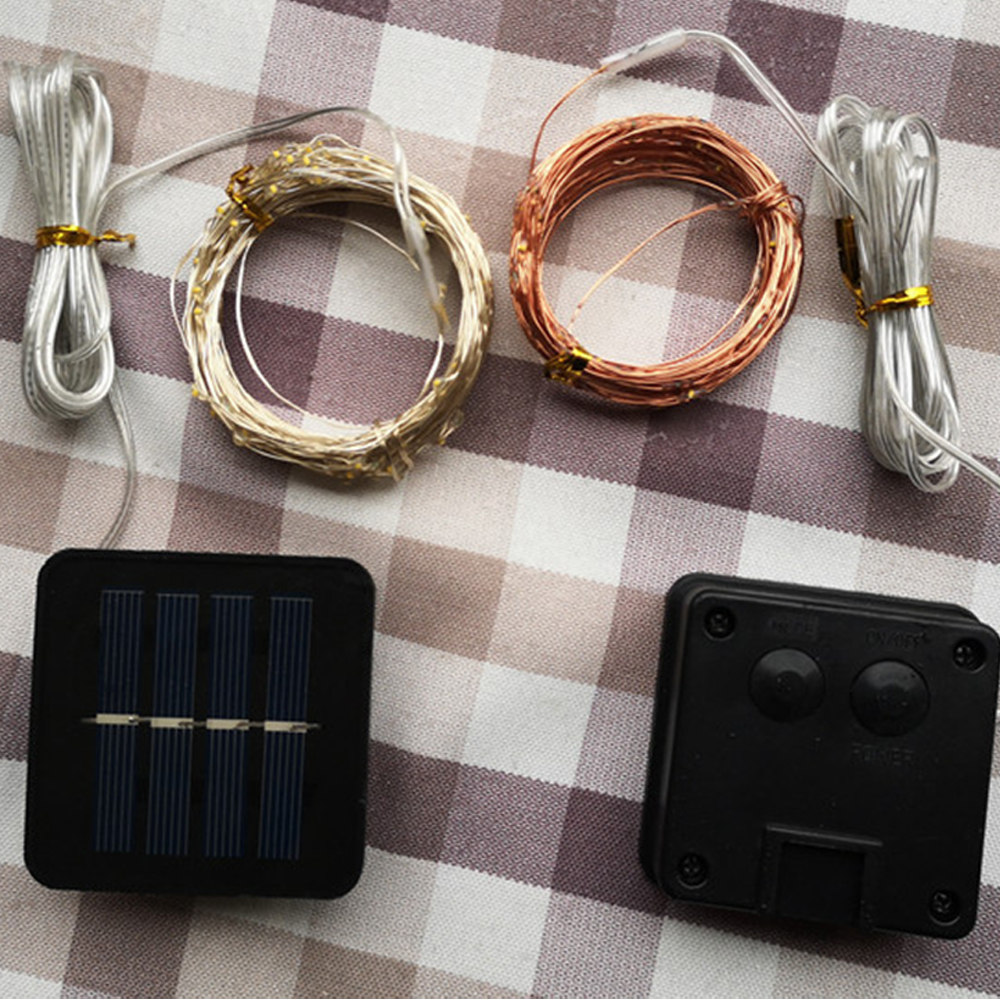 Komponenten von Solarleuchten: zwei Lichtbündel, Solarpanel, Steuerung, alles auf kariertem Stoff.