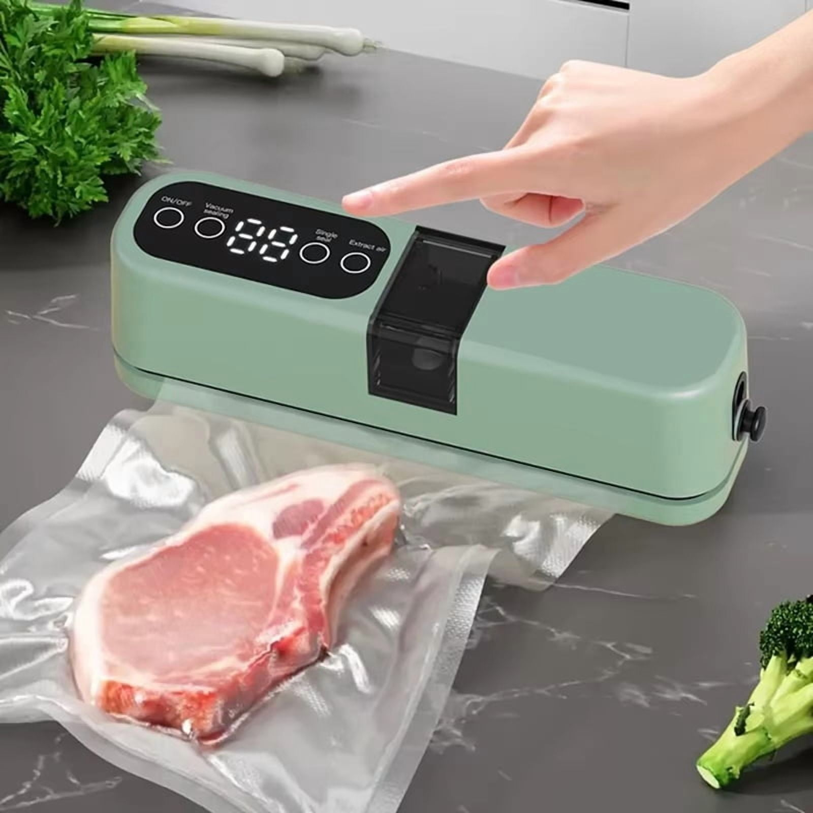 Eine Hand drückt einen Vakuumierer. Ein rohes Schweinekotelett liegt in einer Tüte. Grüne Zwiebeln und Brokkoli sind im Hintergrund.