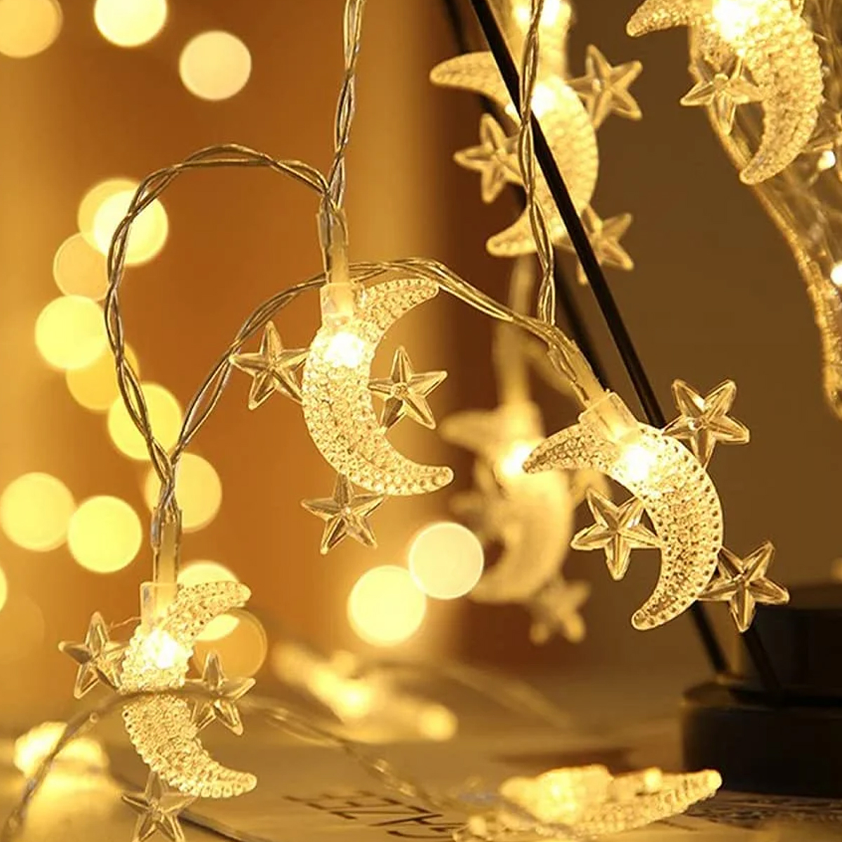 Lichterkette mit leuchtenden Halbmonden und Sternen. Warmes gelbes Licht mit verschwommenem Hintergrund. Festlich und dekorativ.
