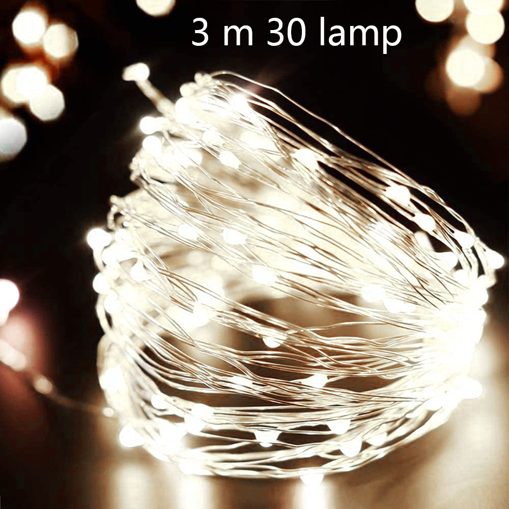 Nahaufnahme einer Schnur aus kleinen, weißen LED-Leuchten, die zusammengerollt sind. Die Lichter sind an, der Hintergrund ist dunkel.