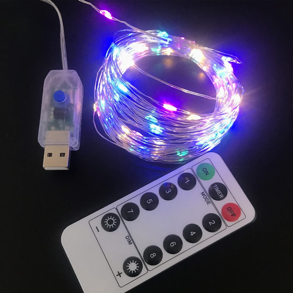 Nahaufnahme von bunten LED-Lichterketten, einer Fernbedienung und einem USB-Anschluss auf schwarzem Untergrund.