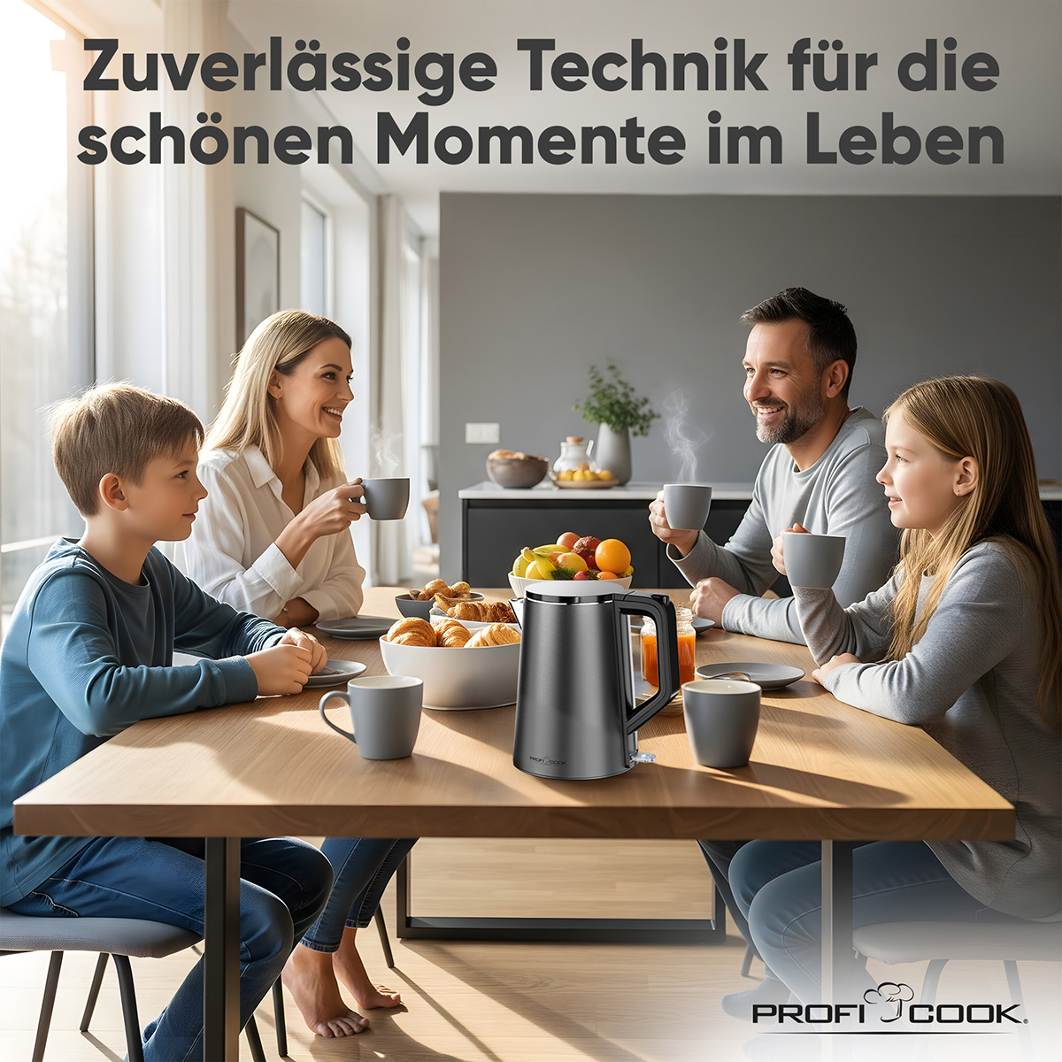 Familie trinkt aus Tassen an einem Holztisch mit einem silbernen Wasserkocher. Obst und Gebäck stehen auf dem Tisch. Die Familie lächelt.