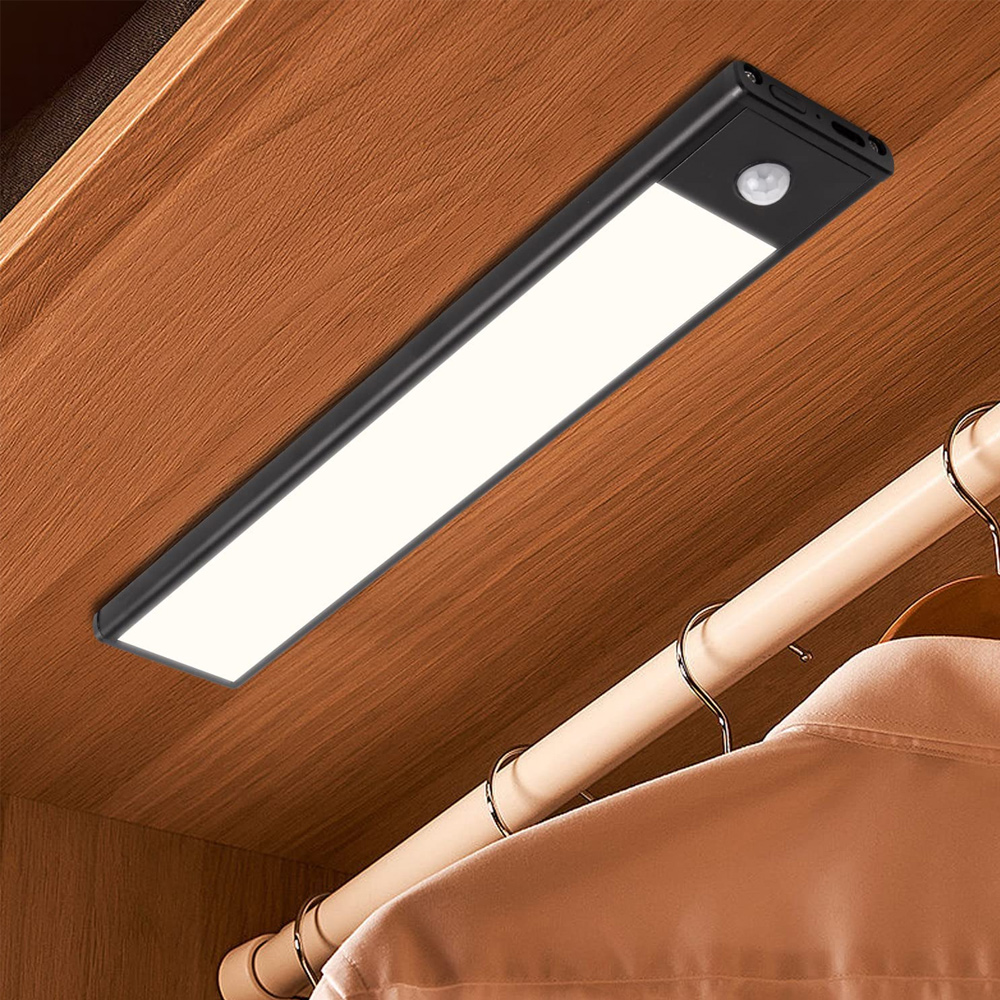 Eine schwarze LED-Leuchte ist in einem Holzschrank montiert. Darunter hält eine Kleiderstange ein Hemd. Die Leuchte hat einen Bewegungssensor.