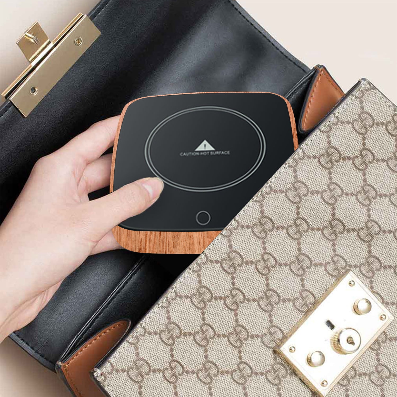 Eine Hand legt einen schwarzen und hölzernen Kaffee wärmer in eine Gucci-Handtasche. Eine andere Tasche ist im Hintergrund.