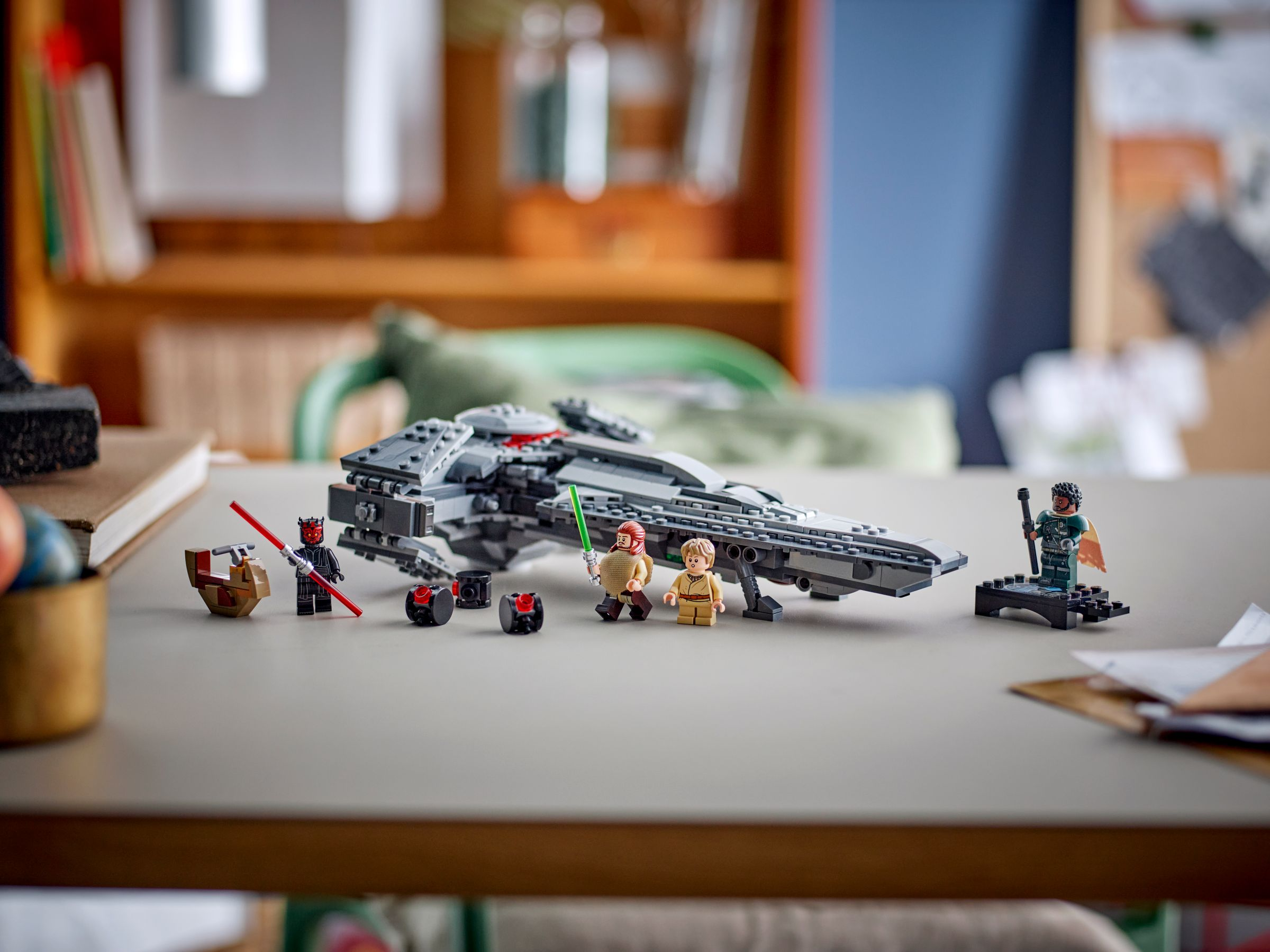 Ein LEGO Star Wars Set steht auf einem Tisch. Minifiguren und ein Schiff sind vorhanden. Hintergrund ist ein Bücherregal und eine blaue Wand.