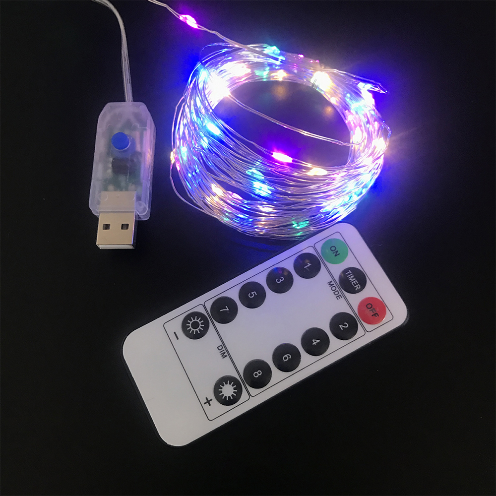 Lichterkette mit USB-Anschluss und Fernbedienung. Lichter sind blau, lila und weiß. Fernbedienung hat Ein/Aus- und Dimm-Tasten.