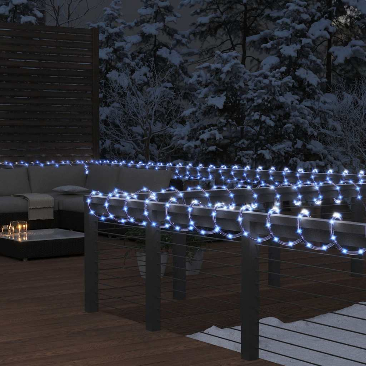 Nachtszenen zeigen eine Terrasse mit blauen Lichterketten an einem Geländer. Ein Sofa, schneebedeckte Bäume und Kerzen sind ebenfalls sichtbar.