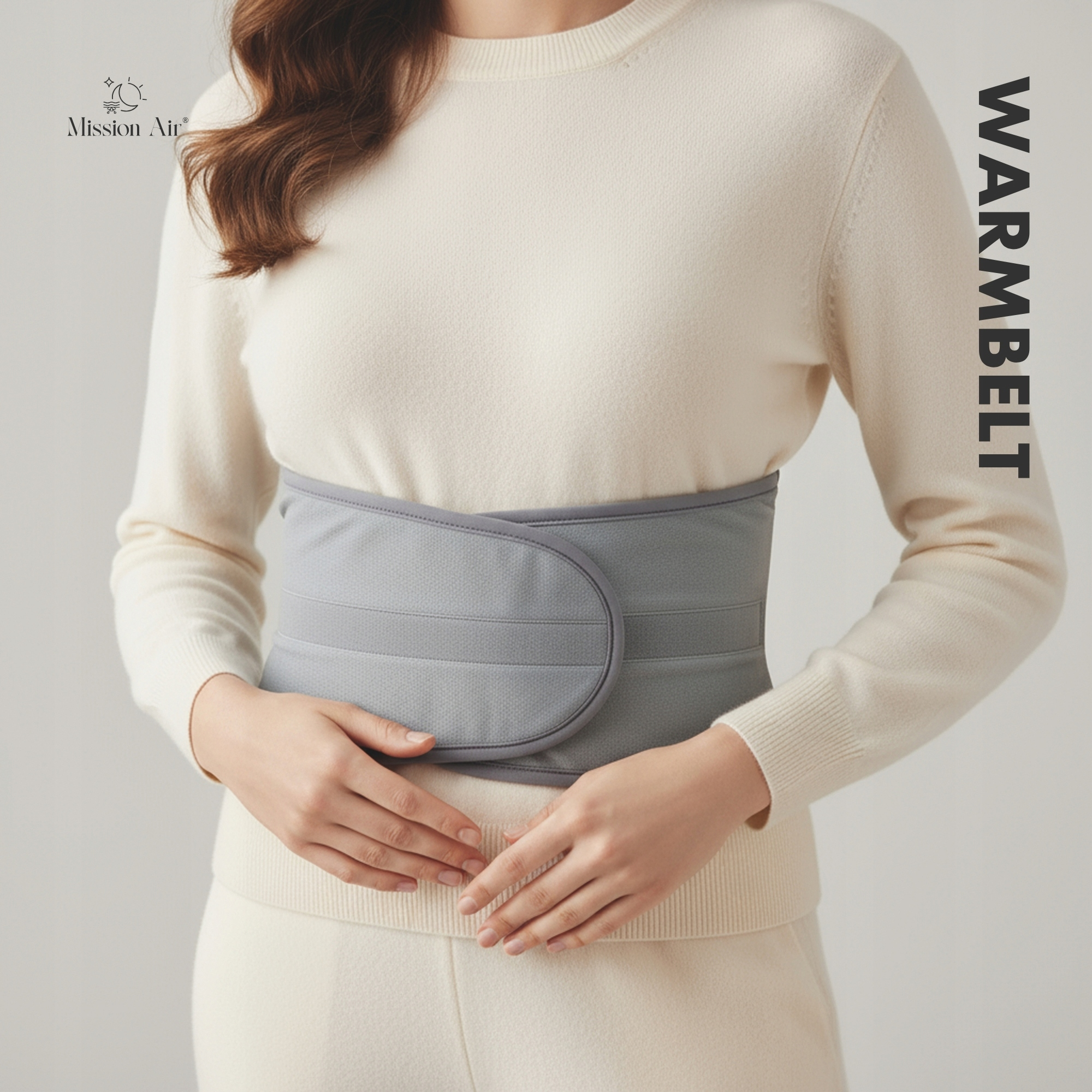 Kobieta ma na sobie szary pas rozgrzewający na kremowym stroju. Pas jest wokół talii. Tekst 'WARMBELT' po prawej.