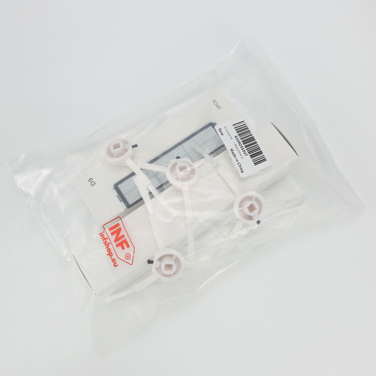 Przezroczysta plastikowa torba zawiera części do odkurzacza: filtry i białe mocowania szczotek, wszystko na białej powierzchni. Etykieta jest widoczna.