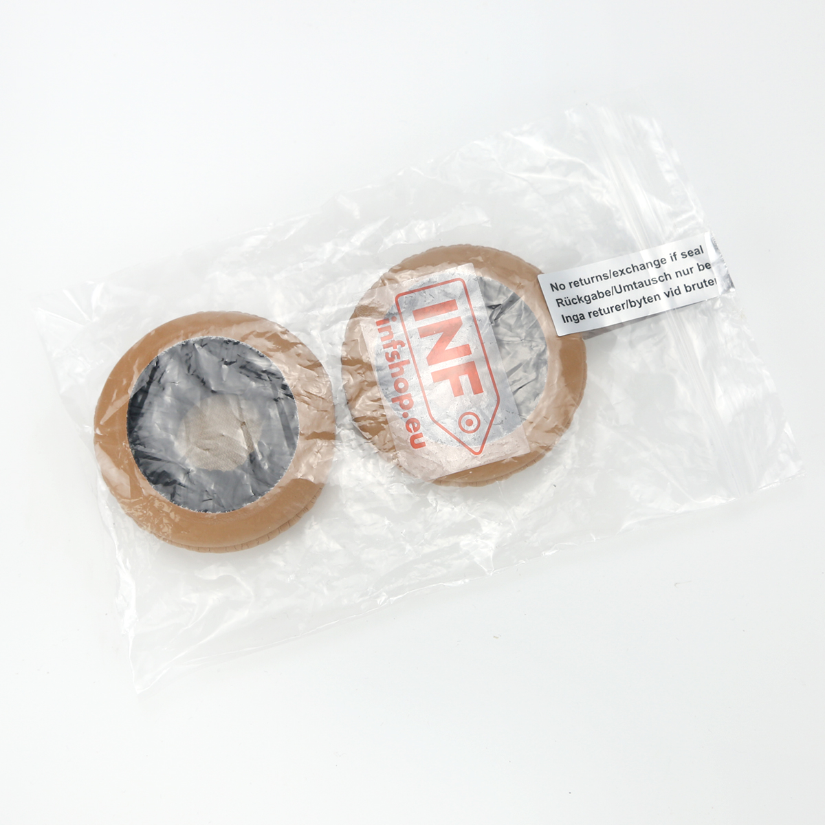 Zwei braune kreisförmige Objekte mit schwarzen Zentren befinden sich in einer Plastiktüte auf weißem Untergrund. Text ist auf der Tüte sichtbar.