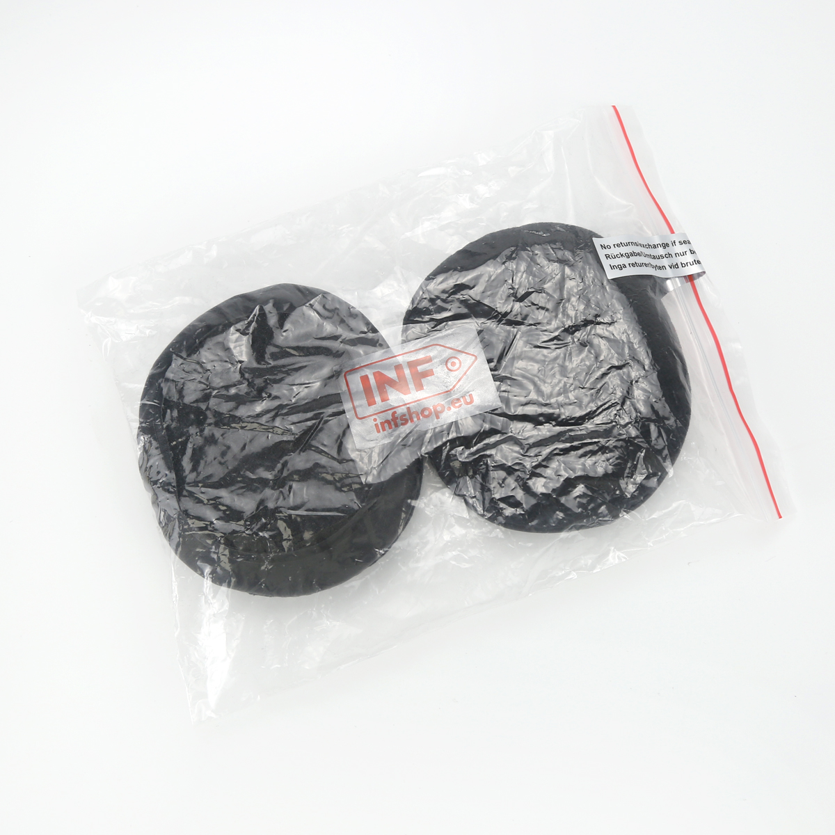 Dwa czarne, okrągłe przedmioty w przezroczystej plastikowej torbie z czerwonym zamkiem błyskawicznym. Widoczna etykieta INF.
