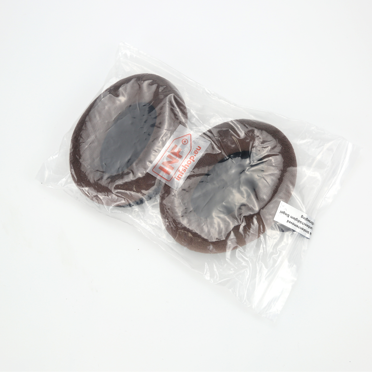 Due cuscinetti marroni in un sacchetto di plastica trasparente su una superficie bianca. La borsa ha un logo e del testo.