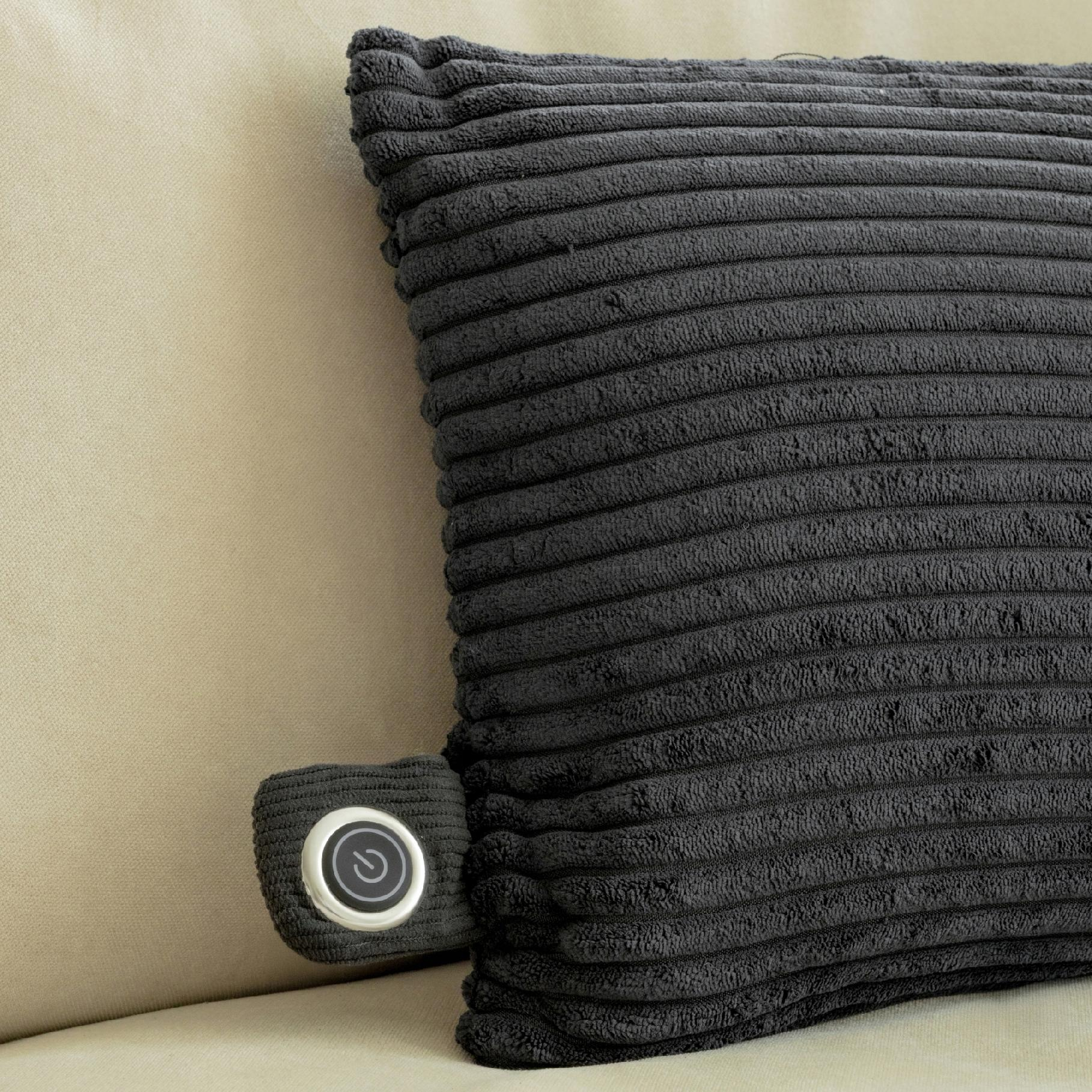 Ciemnoszara poduszka sztruksowa z przyciskiem sterowania na beżowej sofie. Przycisk jest srebrny z symbolem zasilania.