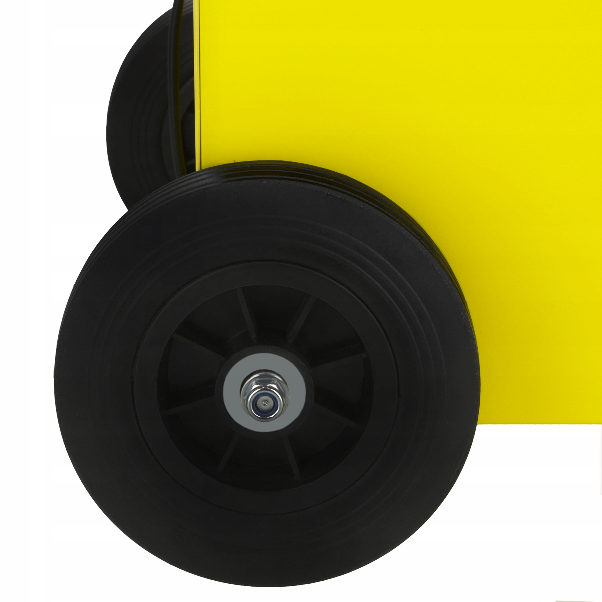 Zbliżenie czarnego koła i żółtej powierzchni. Koło ma srebrny środek. Białe tło.