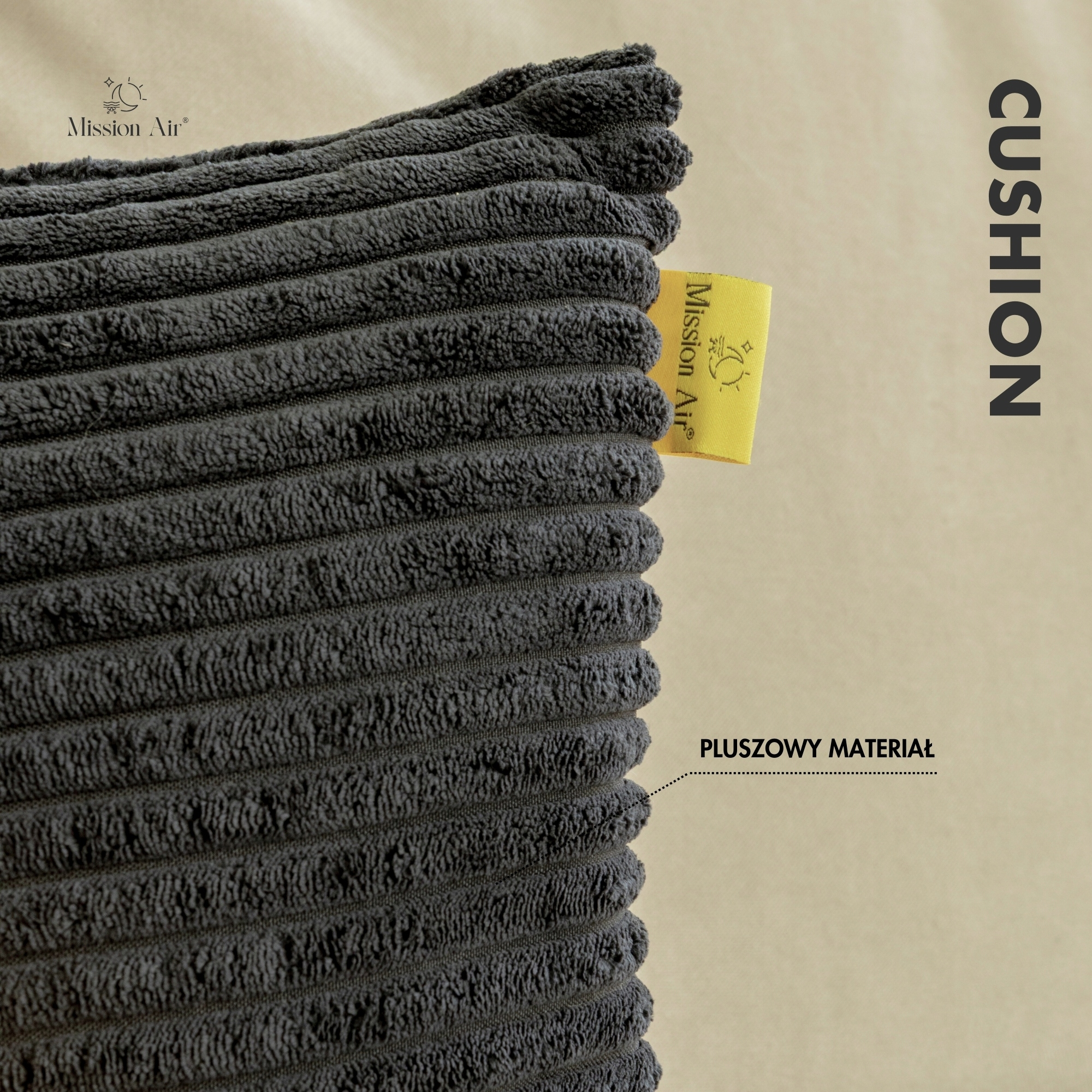 Zbliżenie na ciemnoszarą poduszkę sztruksową. Żółta etykieta z napisem 'Mission Air'. Tekst 'CUSHION' jest pionowy. 'PLUSZOWY MATERIAL'.