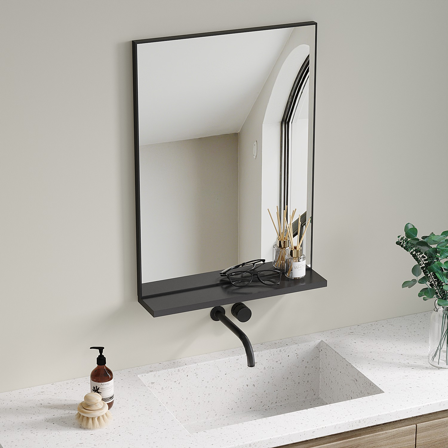 Badezimmer: Spiegel, Regal mit Brille und Diffusoren, Waschbecken, Wasserhahn, Seife, Bürste und Pflanze in einer Vase auf einer Arbeitsplatte.