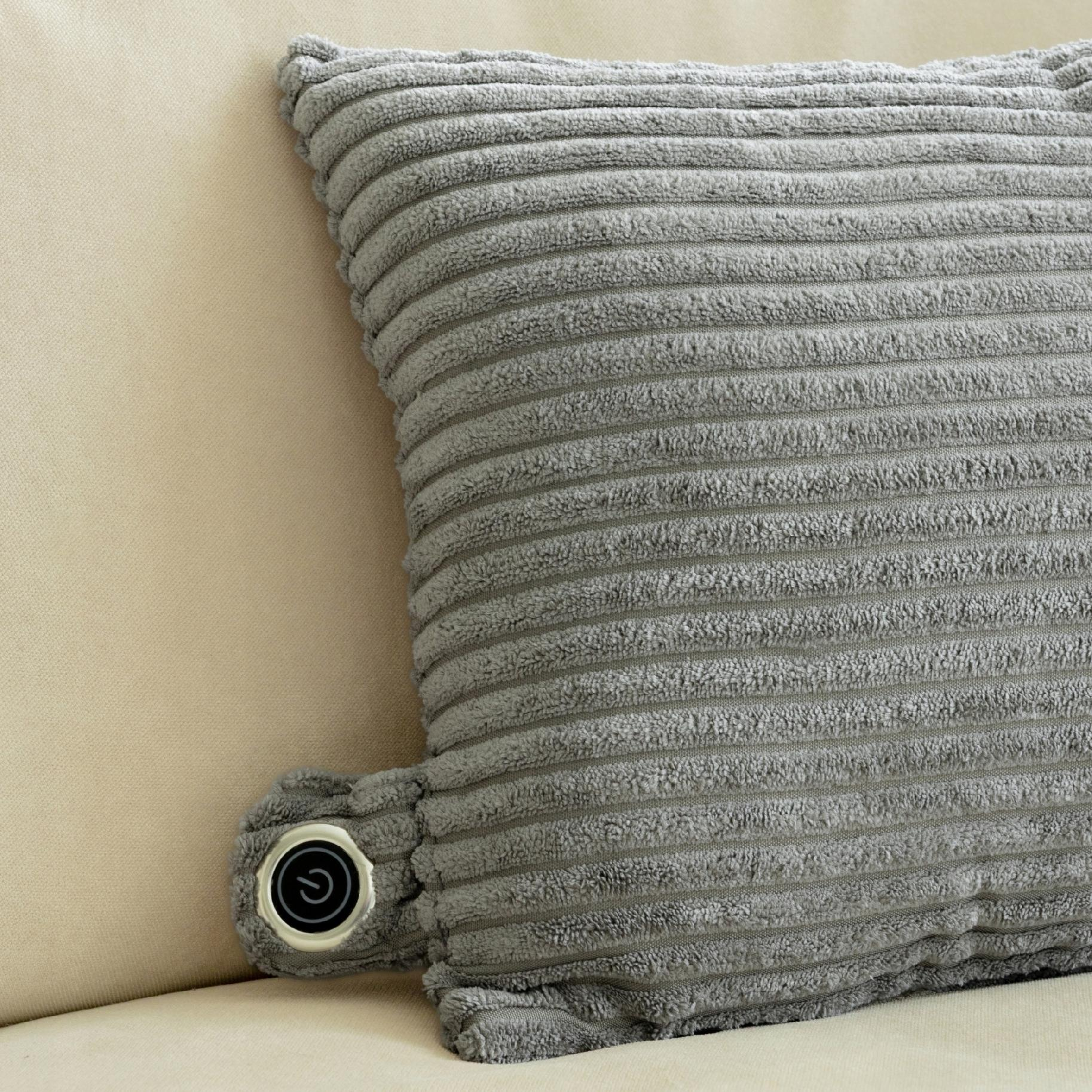 Szara poduszka sztruksowa z przyciskiem zasilania spoczywa na beżowej powierzchni.