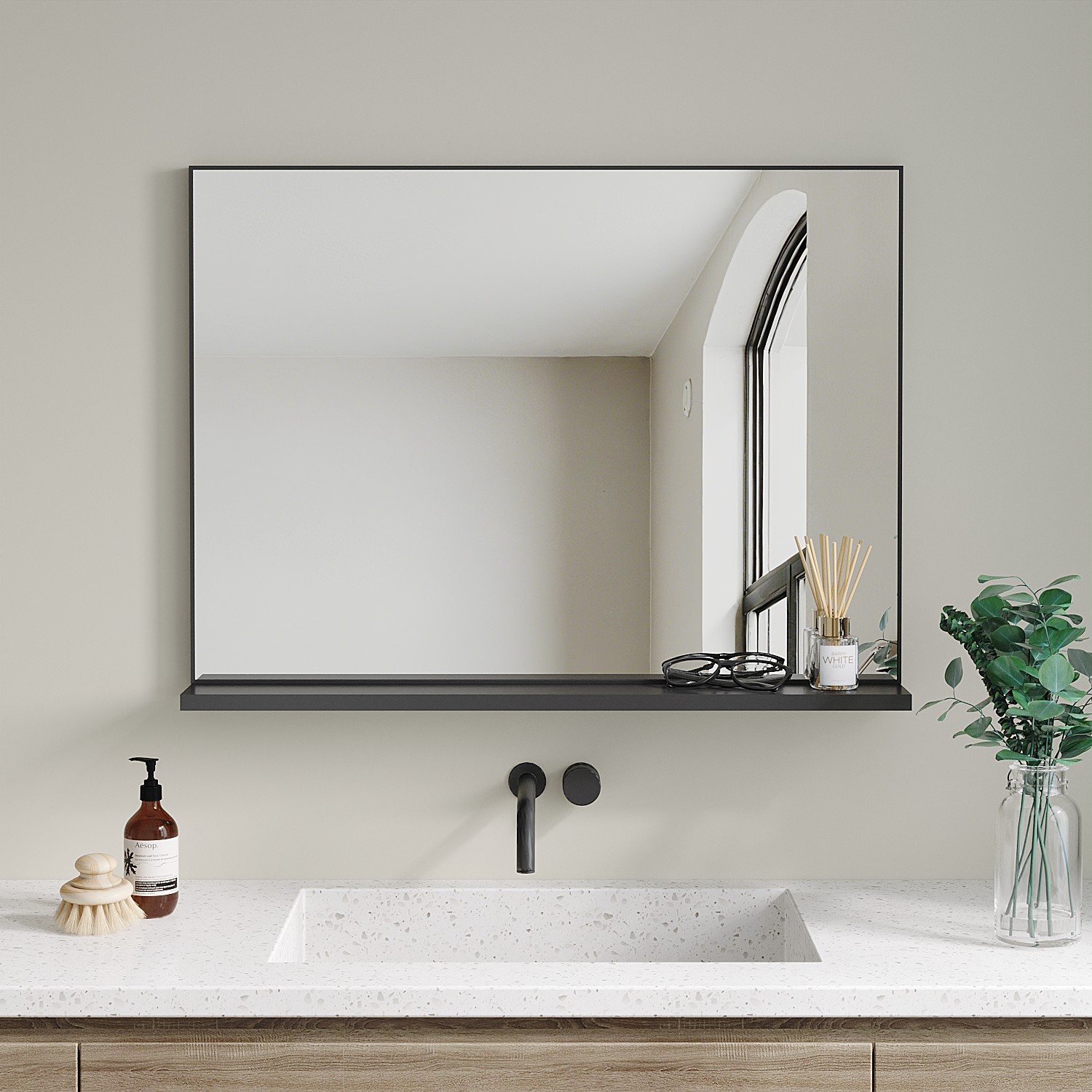 Badezimmer mit Spiegel, Waschbecken und Zubehör. Spiegel reflektiert ein Fenster. Seife, Bürste, Brille und Diffusor stehen auf einem Regal.